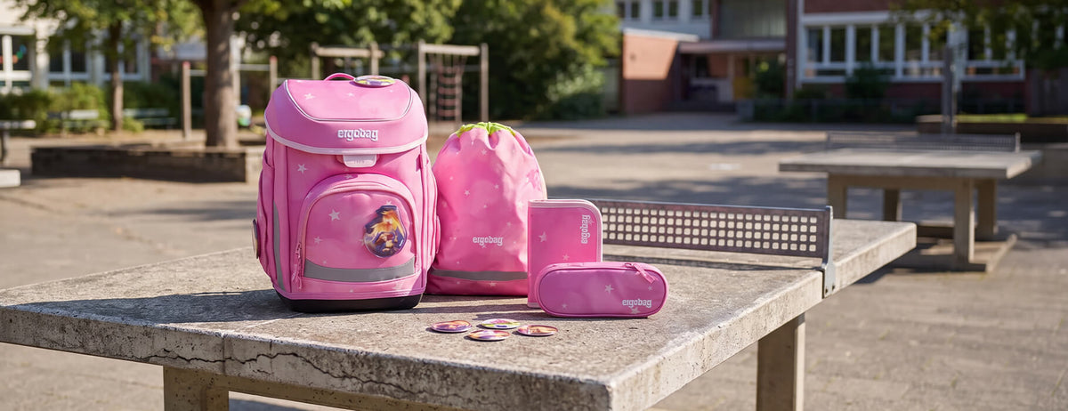 Pinker Ergobag Schulranzen Cubo Wolkenzaubär im Set auf einer Tischtennisplatte